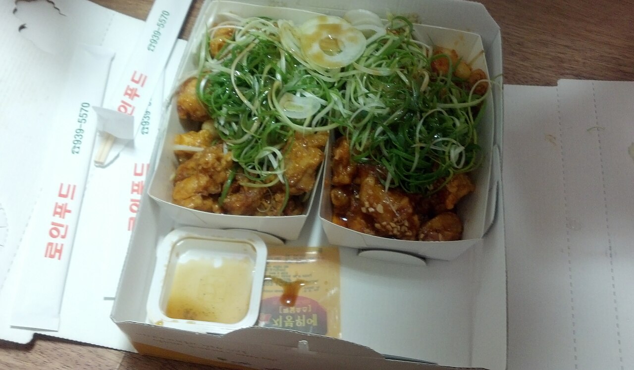 Fried chicken in a box topped with a pile of shredded green scallions