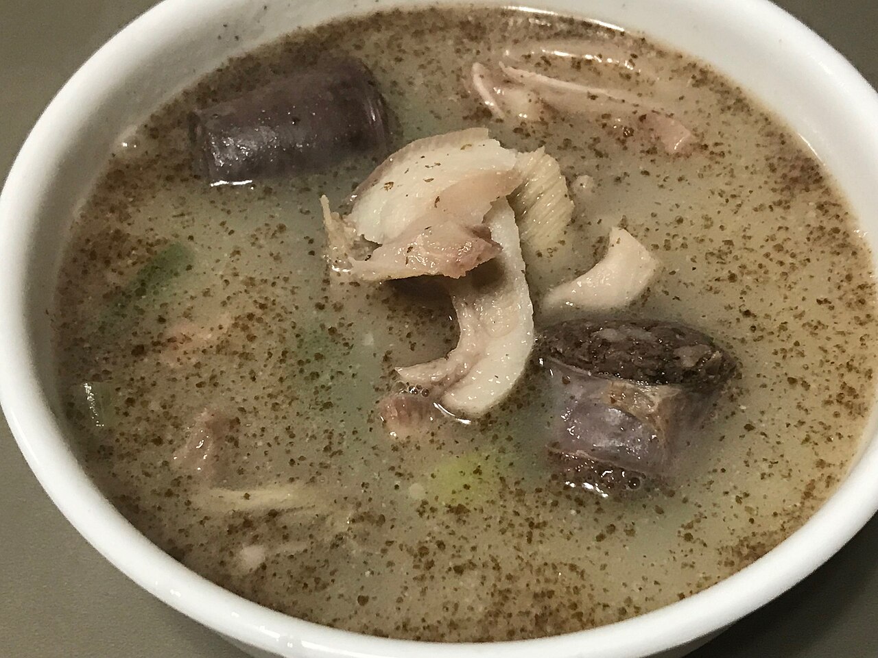 A bowl of sundae-guk with blood sausage slices and pork in a pale broth
