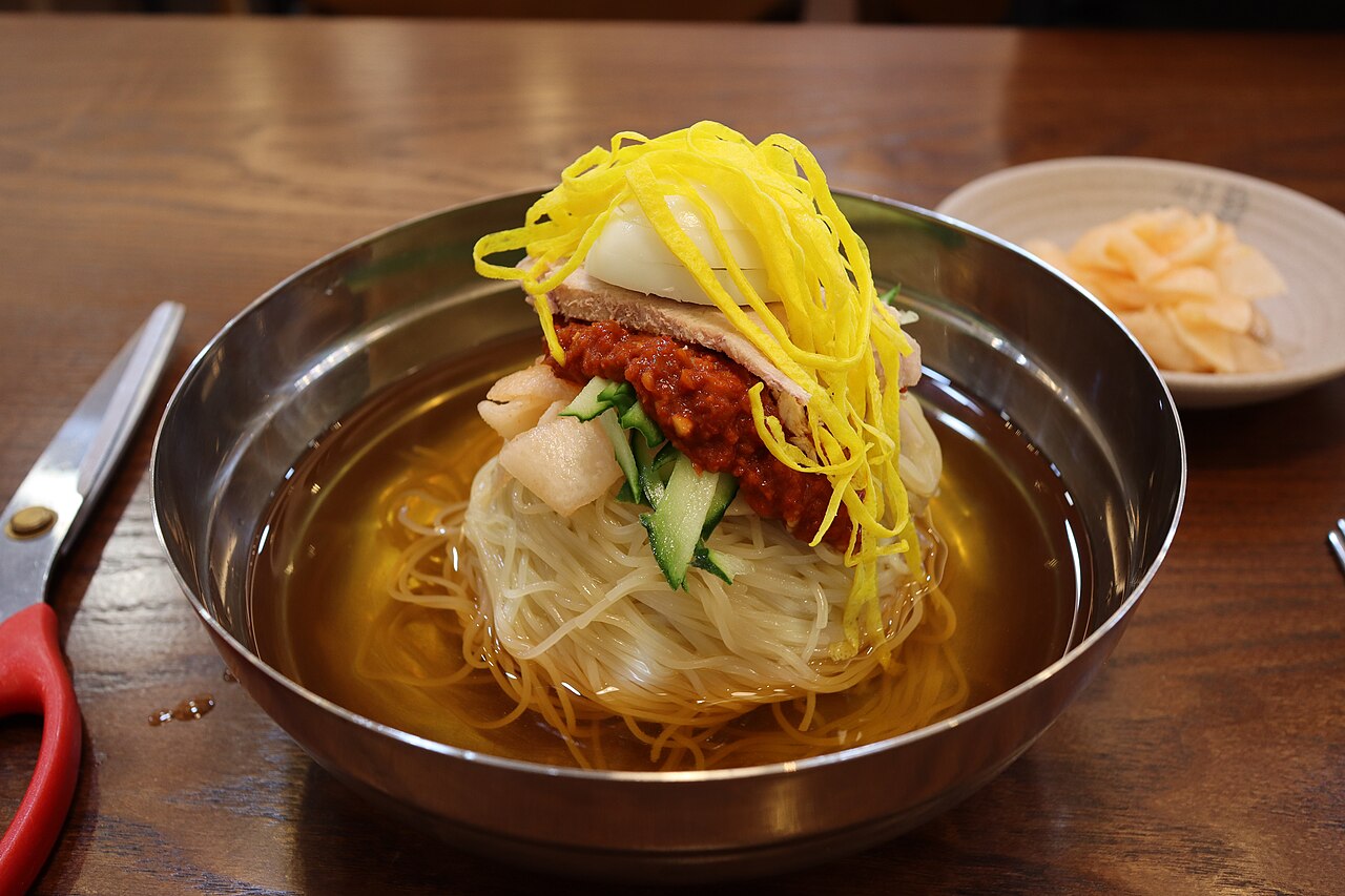 Milmyeon with pale noodles, red seasoning, egg and cucumber in cold broth