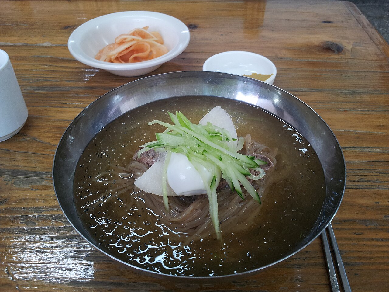 Mul-naengmyeon: noodles in chilled broth with cucumber and radish in a steel bowl