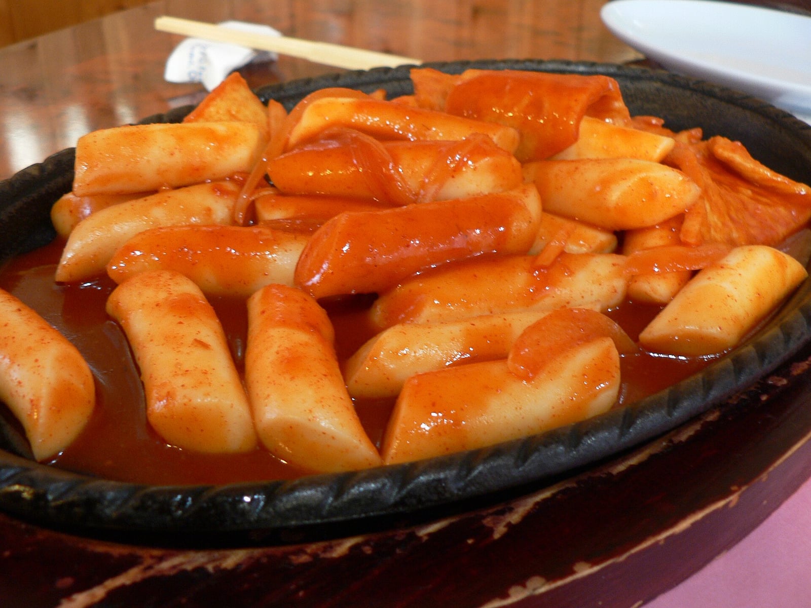 Tteokbokki, rice cakes in red chili sauce, served on a cast-iron plate